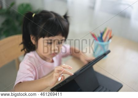 Asian Girl Looking And Touch On White Screen At The Tablet Screen Attentively. Overstimulated Childr
