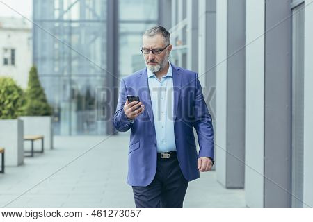 Serious Gray-haired Senior Handsome Man Businessman In Suit And Glasses Walking Near Office Center O