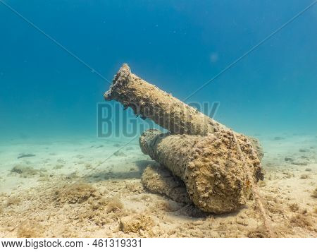 Antique Cannons On A Sandy Sea Floor. Beautiful Turquoise Water In The Background