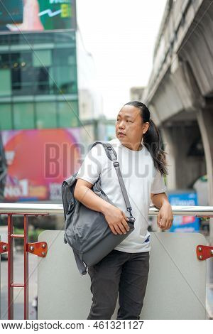 Long Hair Thai, Chinese Man Is Posing In Front Of The Terrace Barricade With Gray Back On The Should