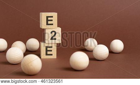 Pyramid Of Wooden Cubes With Text E2e, Wooden Balls On A Brown Background. E2e - Short For End To En
