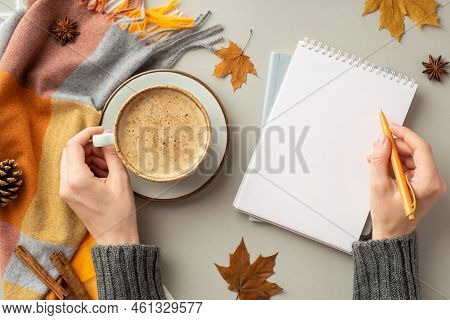 First Person Top View Photo Of Woman's Hands In Pullover Writing In Diary Holding Cup Of Coffee On S
