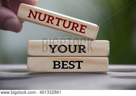 Hand Holding Wooden Block With Text - Nurture Your Best. Motivational Concept.