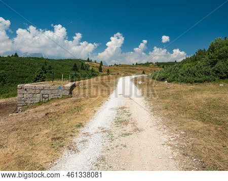 Gravel Road To Hill Peak. Dusty Mountain Road In Dolomite Alps. Enjoy Trekking And Mountaineering.