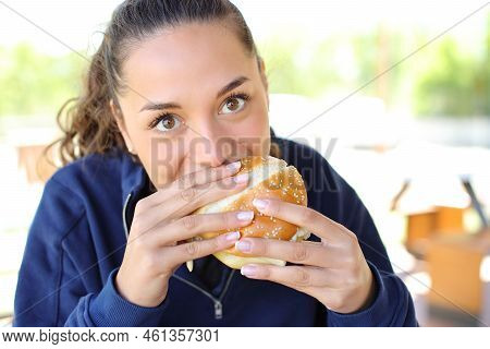 Front View Portrait Of A Woman Eating A Burger Looking At Camera