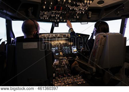 Woman Copilot Assisting Captain To Takeoff And Fly Airplane, Using Buttons On Dashboard Command In P