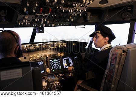 Woman Copilot In Uniform Flying Airplane With Cockpit Command Buttons On Cabin Dashboard. Pushing En