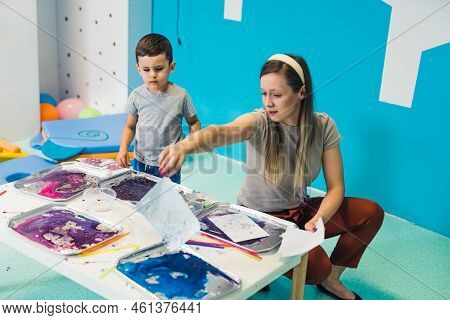 Sensory Play At Multi-cultural Nursery School. Toddlers With Their Teacher Playing With Striped Stra