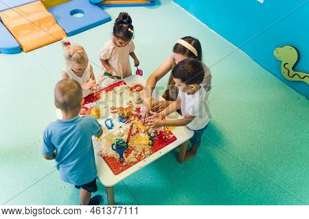 Calming Sensory Play With Moldable Kinetic Sand At Nursery School. Toddlers With Their Teacher Havin