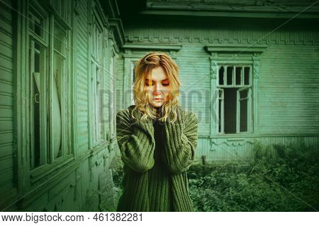 A Sad Woman In A Green Sweater Stands Against The Background Of An Abandoned Forsaken Wooden Green H