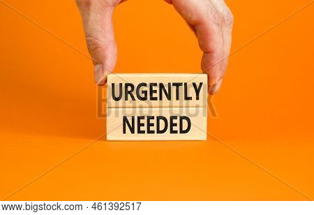 Urgently Needed Symbol. Concept Words Urgently Needed On Wooden Blocks On A Beautiful Orange Table O