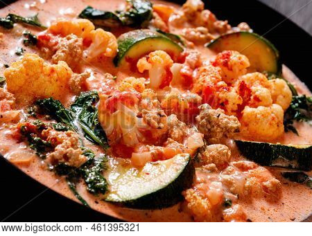 Close-up Of Creamy Tomato Soup With Ground Chicken, Cauliflower, Zucchini, Kale, Basil And Spices In
