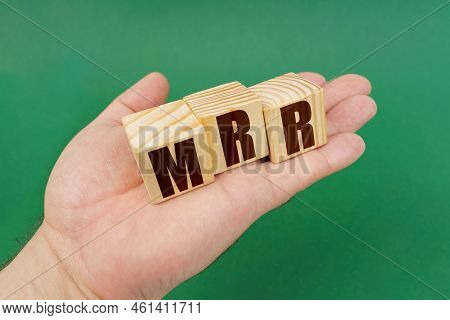 Business Concept. On A Green Background, In The Hands Of A Person, Cubes With The Inscription - Mrr