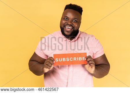 Portrait Of Cheerful Positive Bearded Man Wearing Pink Shirt Holding Red Card With Subscribe Inscrip
