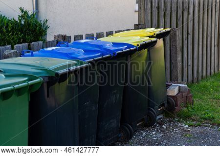 Row Of Plastic Trash Cans Along The Fence. Multicolored Lid.
