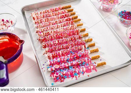 Drizzling Melted Chocolate Over Chocolate-dipped Pretzels Rods And Decorating With Sprinkles To Make