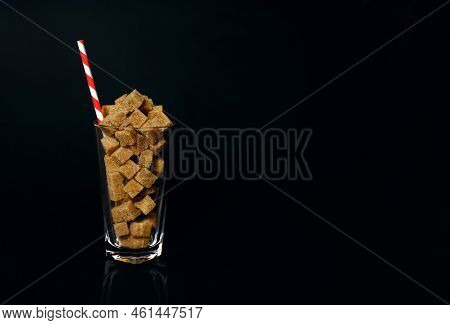 Cane Sugar Slices In A Glass With A Red And White Drinking Straw On A Black Background. The Notion O