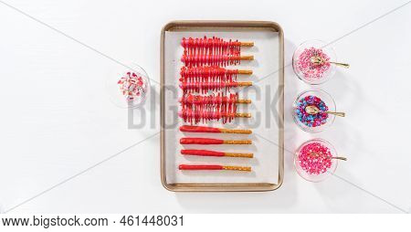 Flat Lay. Drizzling Melted Chocolate Over Chocolate-dipped Pretzels Rods And Decorating With Sprinkl