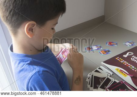 Bauru, Brazil - 12.09.22: Back View Of Boy Opening Sticker Packs To Paste In Panini Fifa World Cup 2