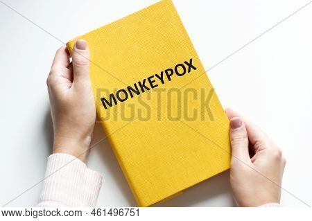 Monkeypox Concept. Monkeypox Text On The Cover Of A Notebook In The Hands Of A Doctor On A White Bac