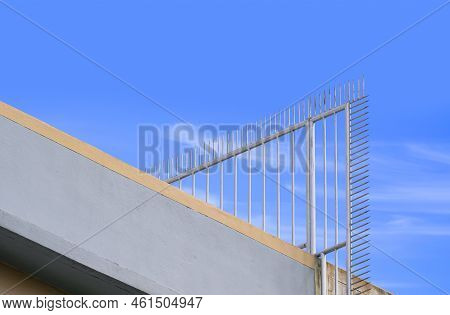 Low Angle View Of Metal Spike Fence On Rooftop Of Tenement Building For Security Concept