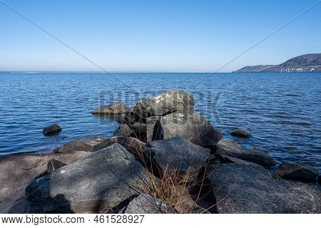 Boulders As A Part Of A Wave Breaker In A Lake. Picture From Lake Vattern, Sweden. Blue Water And Sk