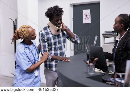 Patient With Medical Neck Foam Receiving Support And Help From Nurse And Receptionist, Giving Treatm