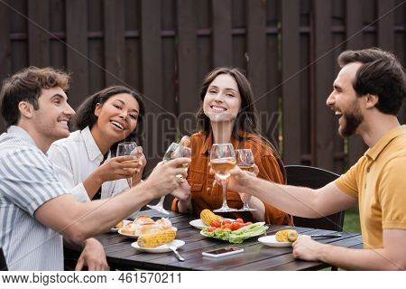 Cheerful Multiethnic Friends Clinking Glasses With Wine And Having Lunch During Bbq Party.