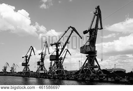 Bulk Cargo Terminal In Port With Many Shore Cranes And Piles Of Coal And Wood Chips, Black And White