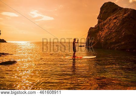 Side View Foto Of A Man Swiming And Relaxing On The Sup Board. Sportive Man In The Sea On The Stand 