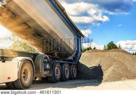 A Large Dump Truck Unloads Rubble Or Gravel At A Construction Site. Car Tonar For Transportation Of 