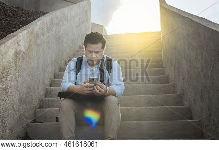 Handsome Man Sitting On Stairs Using Smart Phone, Front View Of Guy Sitting On Stairs Using His Cell