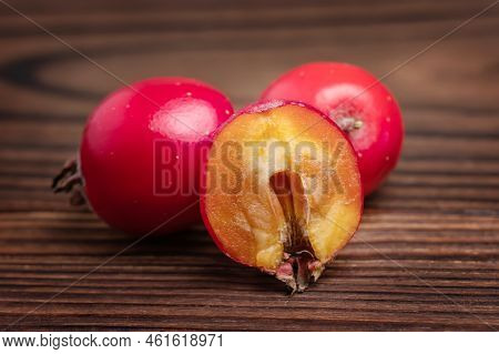 Hawthorn Berries And Half Berrie Slice On Wooden Background.