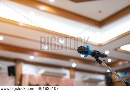 Close Up Microphone On Stand, Empty Event Hall Blurry Background. Mic  For Speaker Speech In Seminar