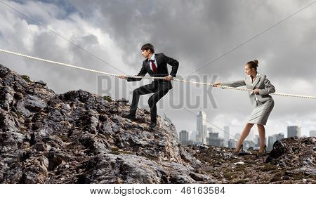 Imagem de busionessman e empresária puxando a corda no topo da montanha