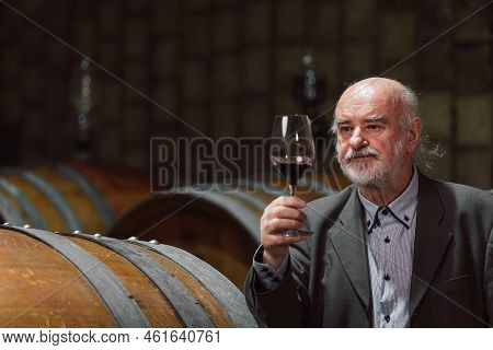Senior Caucasian Tourist, Greybeard Elegant Man Tasting Red Wine In An Underground Wine Cellar Of Th