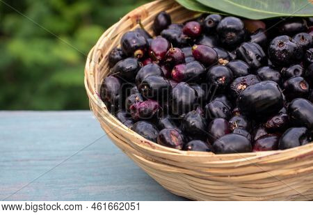 Closeup Of Jamun Or Syzygium Cumini In A Bamboo Basket On Wooden Background With Copy Space, Also Kn