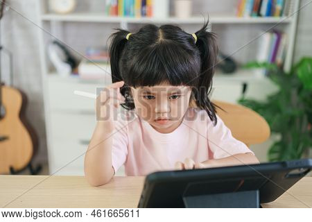 Asian Girl Looking And Touch On White Screen At The Tablet Screen Attentively. Overstimulated Childr