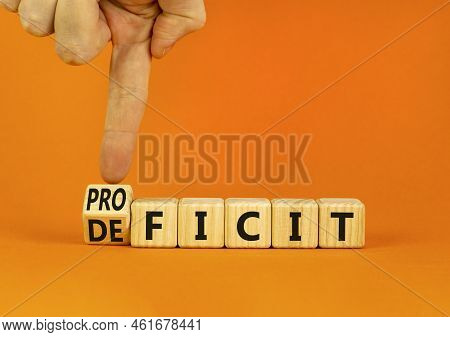 Proficit Or Deficit Symbol. Businessman Turns Wooden Cubes And Changes The Concept Word Deficit To P