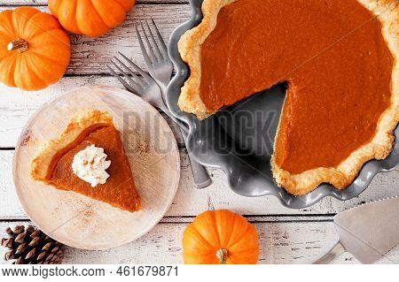 Slice Of Pumpkin Pie With Whipped Cream Topping. Top View Table Scene On A White Wood Background.