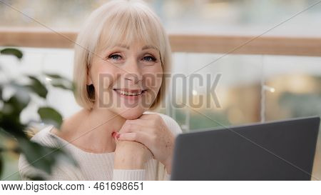 Happy Calm Mature Middle Aged Woman Sitting Resting Relaxing Holding Hands Under Chin Looking At Lap
