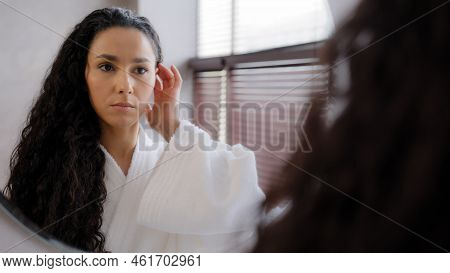 Worried Upset Young Woman Standing In Bathroom In Bathrobe Reflected In Mirror Looking At Split Ends