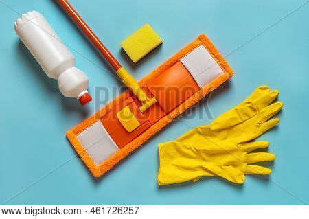 Flat Dust Mop And Rubber Gloves On A Blue Background. Orange Microfiber Mop, Yellow Gloves, Bottle O