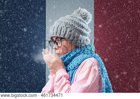 Energy Crisis In Europe. French Woman In Hat And Scarf Is Breathing And Coughing. In The Background 