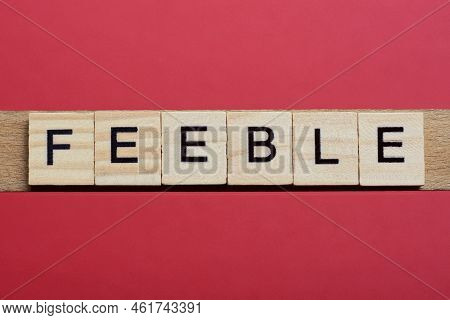Text The Word Feeble From Gray Wooden Small Letters With Black Font On An Red Table