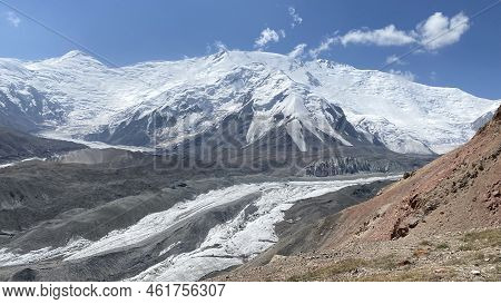 Amazing View Of The Snow-capped Pamir Mountains. Rocks, Hills And Glacier Under Lenin Peak. Beautifu