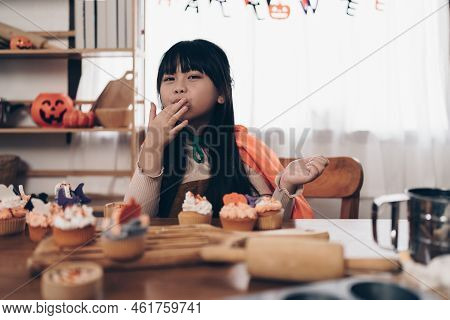 Young Girl At Halloween Making Treats And Cupcake On Table. Happy Halloween Day