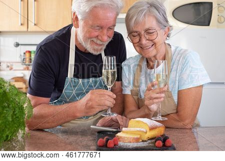 Beautiful Senior Couple In The Home Kitchen Looking At Their Homemade Plumcake Ready To Eat, Holding