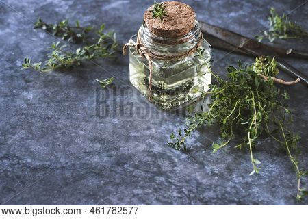 Thyme Oil In Bottle, Freshly Cut Thymus Serpyllum Leaves On Table, Copy Space