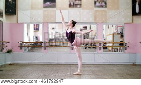 In Dancing Hall, Young Ballerina In Black Leotard Performs 1 Arabesque, Raises Her Leg Up Behind Ele